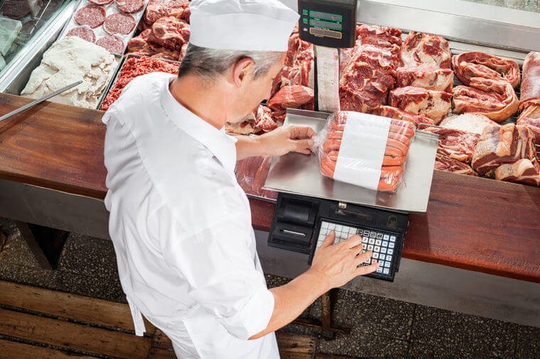 взвешивает мясо на весах