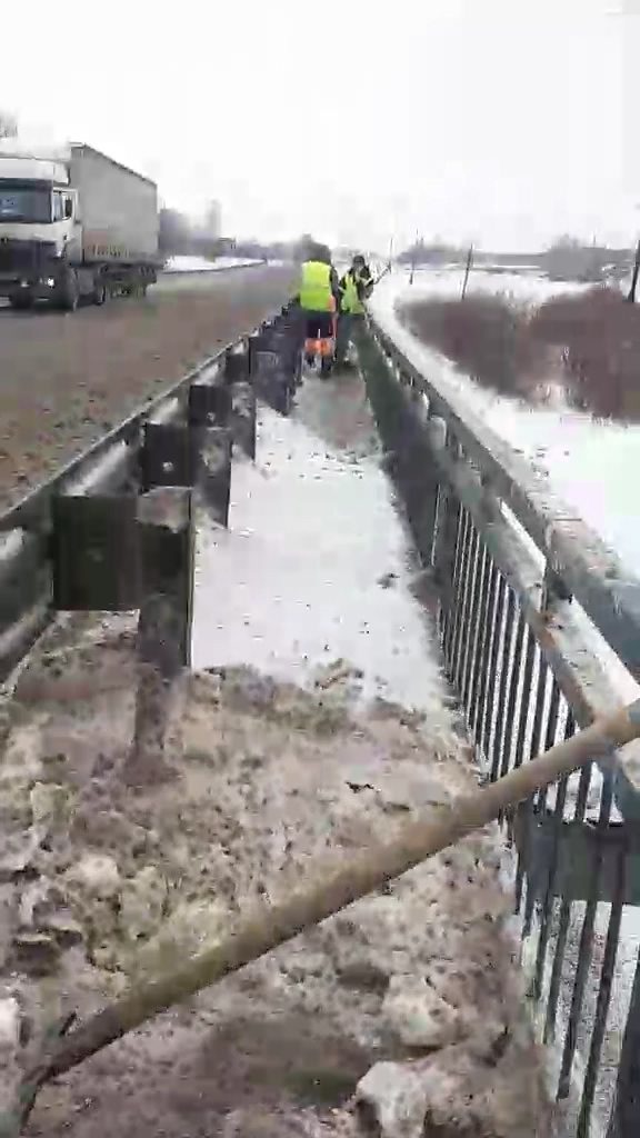 рабочие чистят снег зимой на мосту